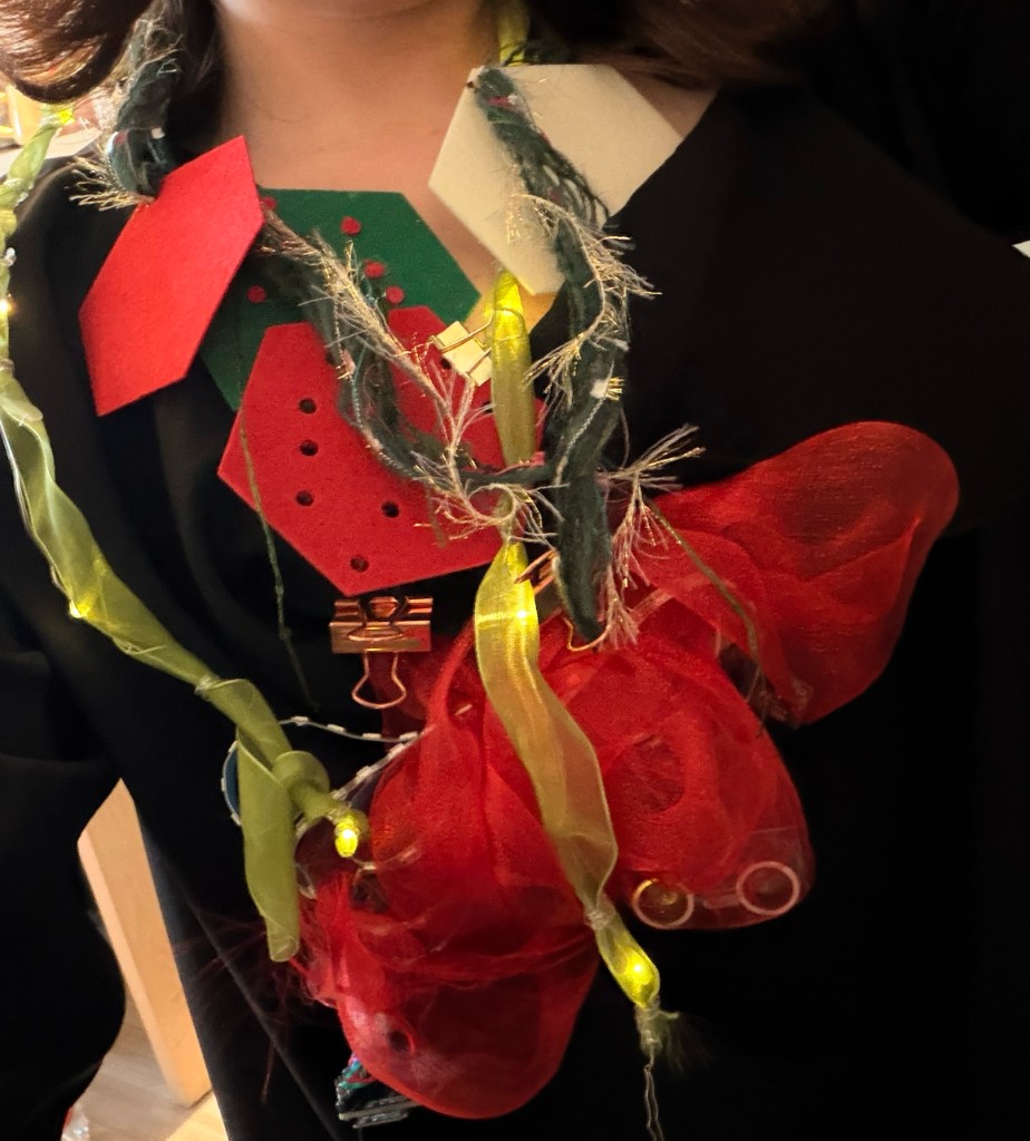 深色上衣前襟：红色与绿色六边形毛毡、纱质织物与点亮的灯串